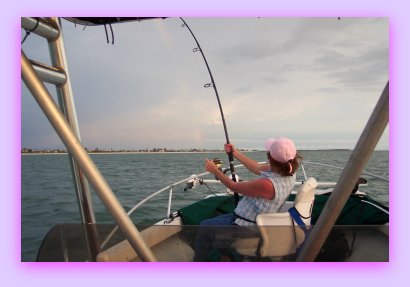 Sharon Masters fighting a Tarpon and looking at a sun set.